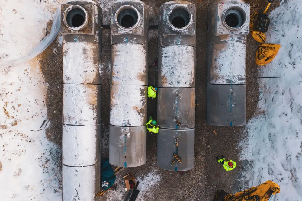Dronefoto av rørseksjoner og anleggsarbeidere på vinteranlegg