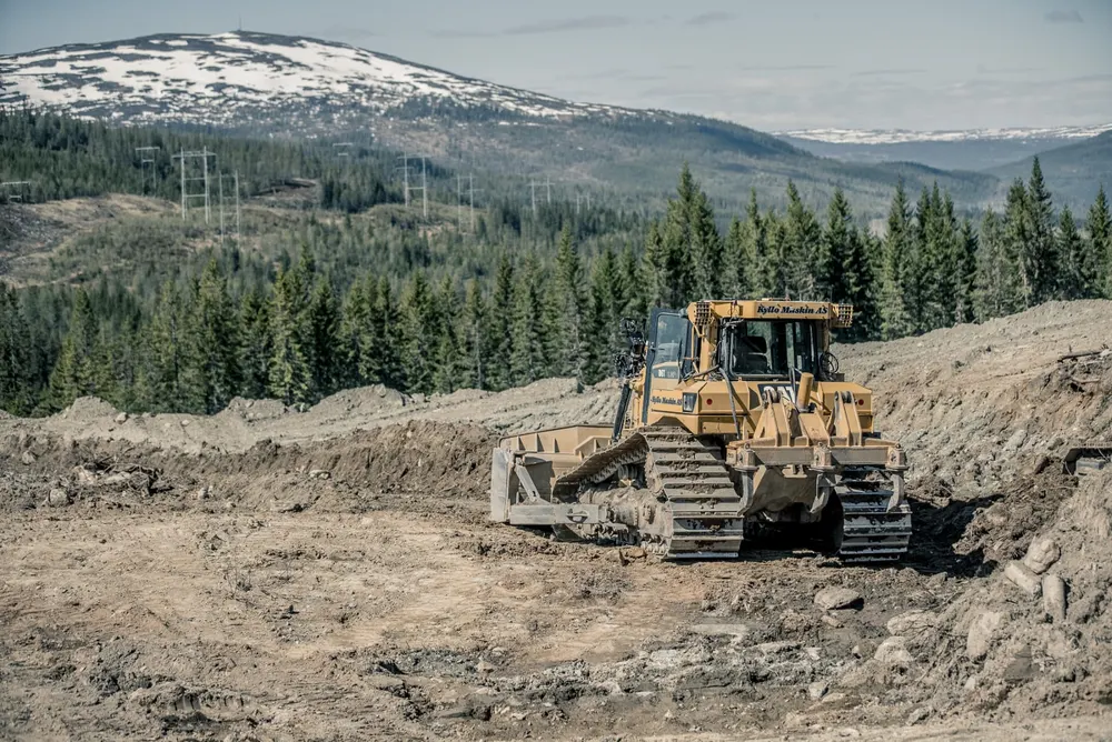 Kyllo Maskin-bulldoser i maskinpark mot fjellandskap