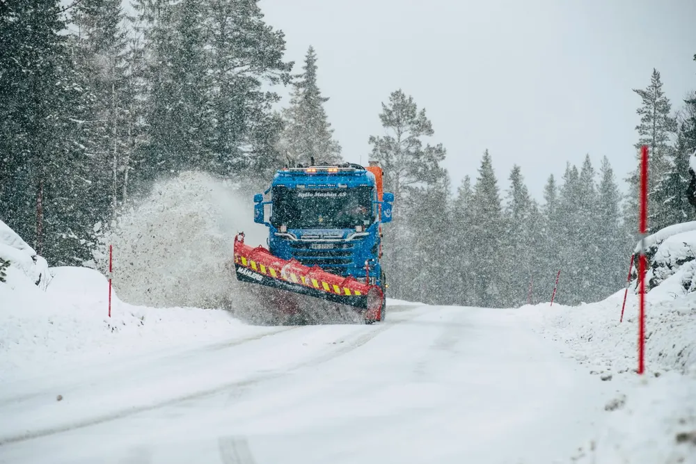 Snørydder med Mählers-plog kaster snø i vegg av snø på vintervei